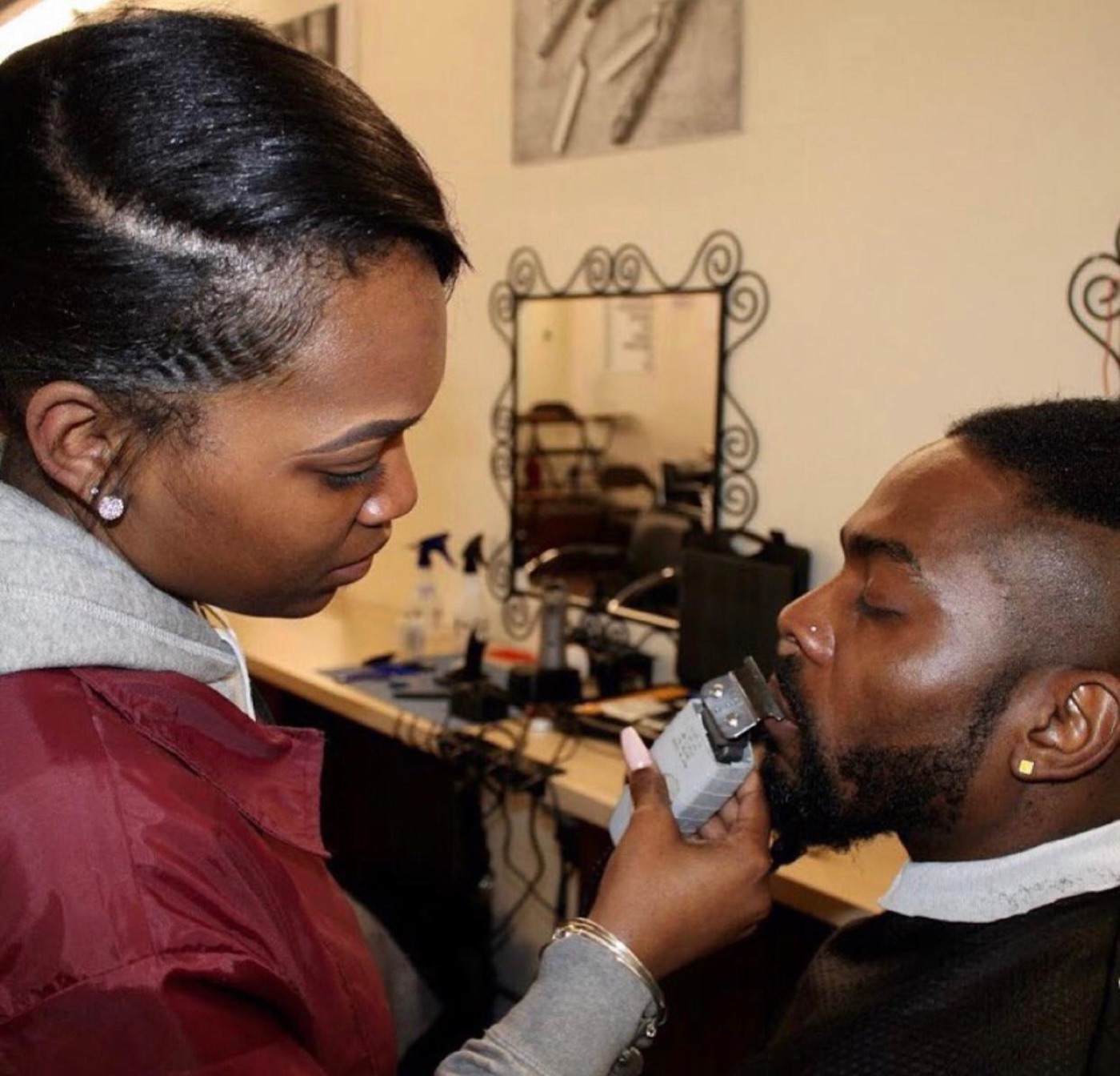 Student trimming client's beard with clippers