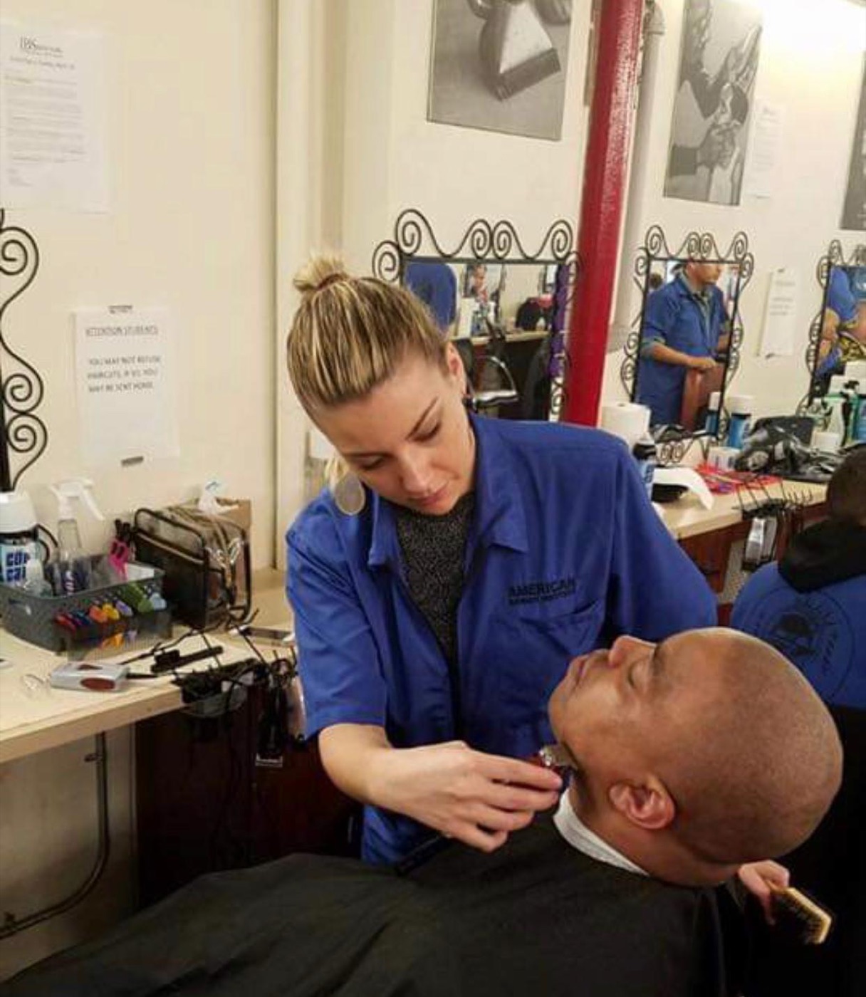 Student shaving client beard at station