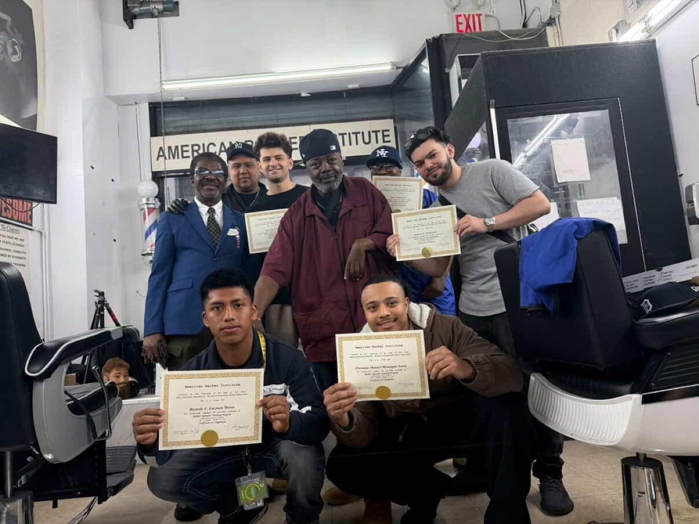 A graduating class of ABI students with their instructor, proudly holding completion certificates