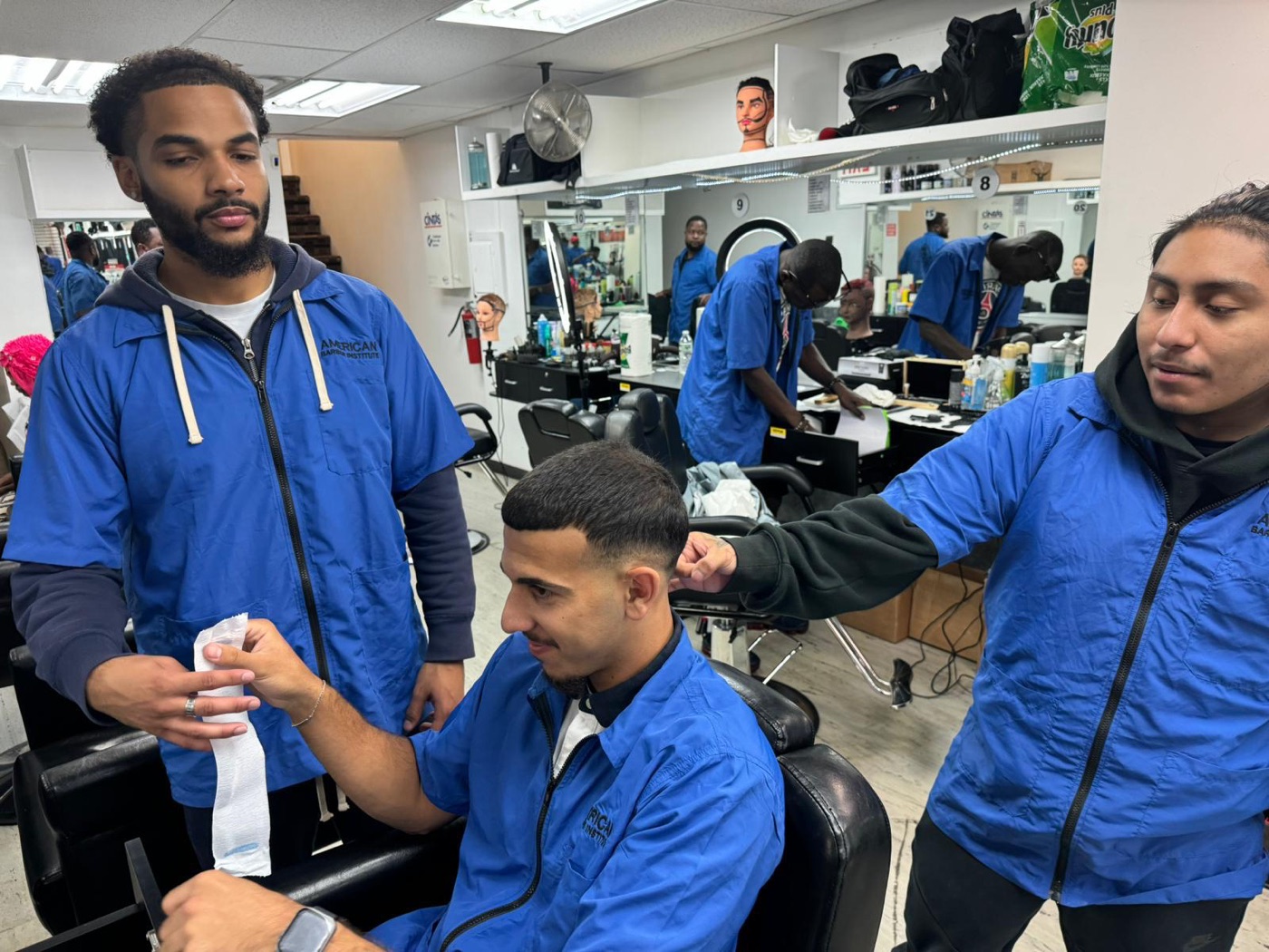 ABI students guiding one another around the barber chair during a lesson